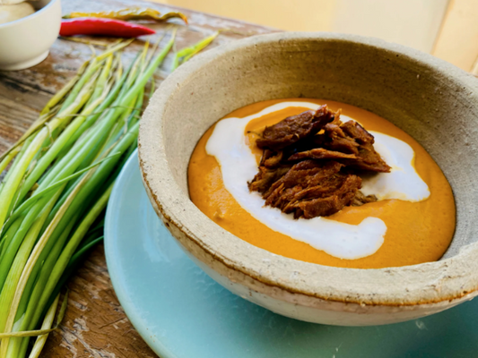Bowl of soup with Let Them Eat Vegan NOT Beef on a wooden table