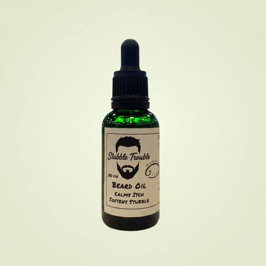 Bottle of 'Stubble Trouble' beard oil on a wooden table with a blurred indoor background