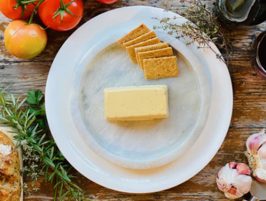 Let Them Eat Vegan Cheddar Block on a plate with crackers and vegetables on a wooden table