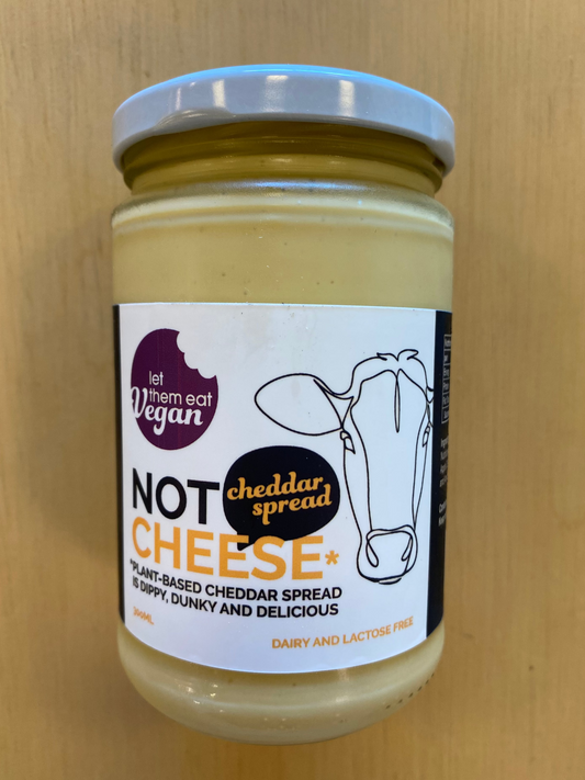 Jar of Let Them Eat Vegan Not Cheese vegan Cheddar Spread with a vegan label on a wooden surface