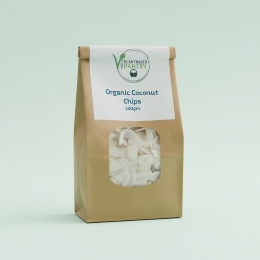 A 200g bag of PlantBased Pantry Organic Coconut Chips on a wooden table, with a brown kraft paper bag and a white label.