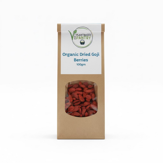 A 100g paper bag of PlantBased Pantry Organic Dried Goji Berries, displayed on a wooden surface. The kraft paper bag features a white label with blue text and a clear window showing the dried red-brown berries inside.