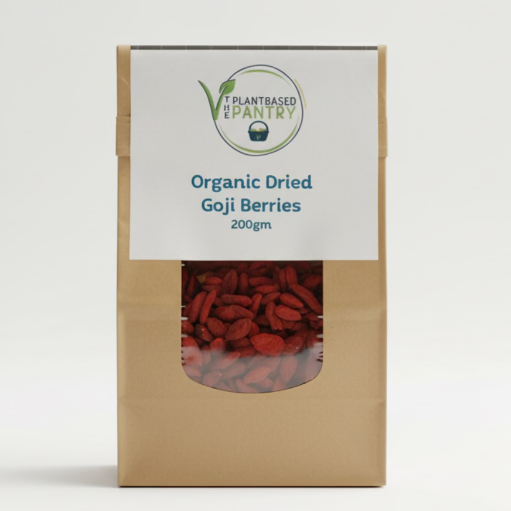 A brown kraft paper bag of PlantBasedPantry Organic Dried Goji Berries, 200g, standing on a wooden table with a blurred indoor background.