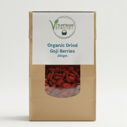 A brown kraft paper bag of PlantBasedPantry Organic Dried Goji Berries, 200g, standing on a wooden table with a blurred indoor background.