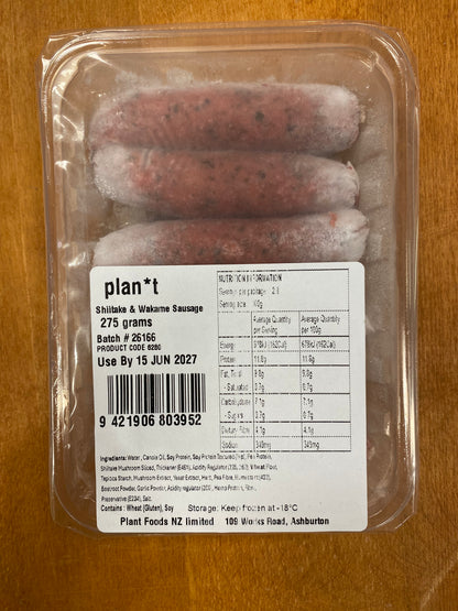 A 275g package of Plan*t Skillet & Wok Sausage in a clear plastic clamshell container with a white nutrition label, placed on a wooden surface.