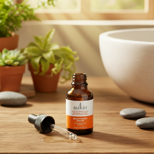 Sukin Natural Actives Brightening serum bottle with dropper on a beige background