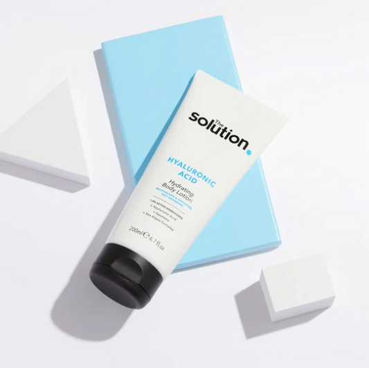Tube of 'The Solution' Hyaluronic Acid Hydrating Body Lotion on a light blue box with a white background.