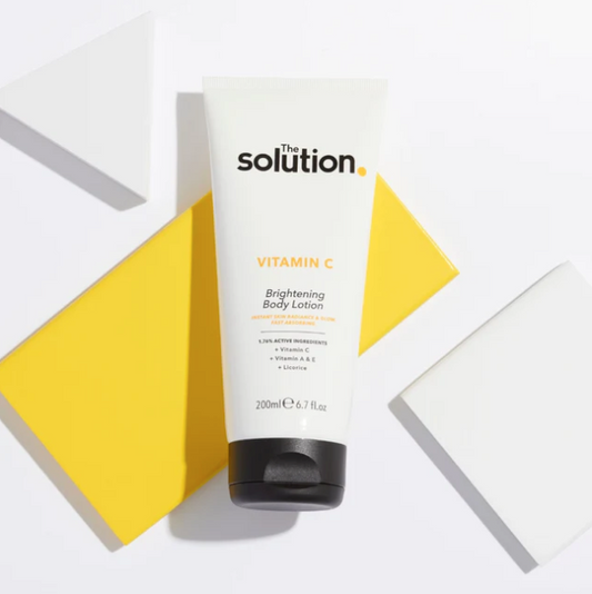 Tube of 'The Solution' Vitamin C Brightening Body Lotion on a geometric background