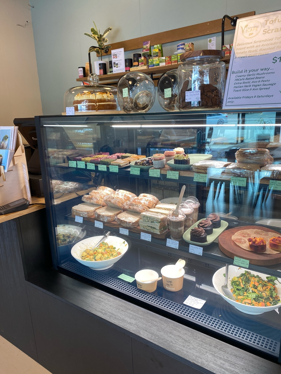 image of PBCafe cabinet filled with vegan food opions, from snacks & treats, to hearty & healthy salads